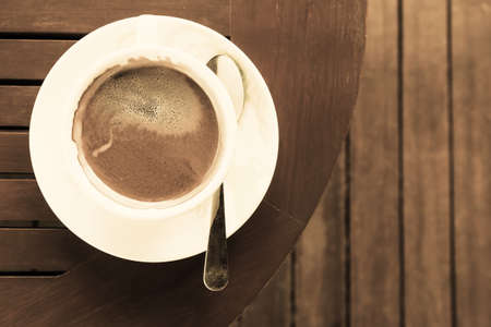Coffee cup with rich coffee  on a brown wooden table vintage style