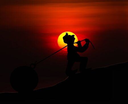 Concept man with pulling a heavy load ball silhouette with sunset backgroundの写真素材