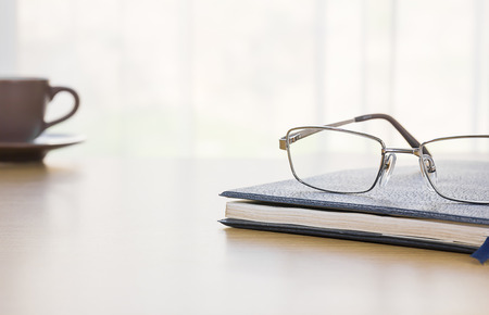 Glasses on a book with on the desk by nature backgroundの写真素材