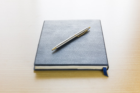 Pen on a book with deck wood backgroundの写真素材
