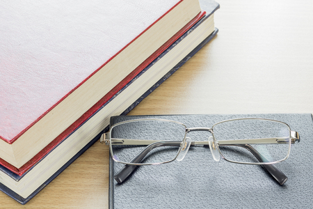 Glasses put on notebook on deck woodの写真素材