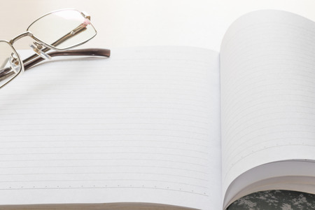 Eyeglasses and Notepad with blank page on wood tableの写真素材