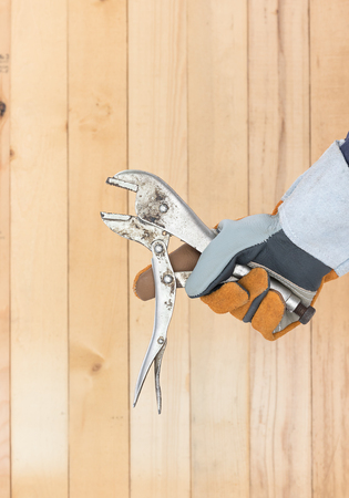 Working hand in glove holding a Adjustable wrench with wall wood backgroundの写真素材
