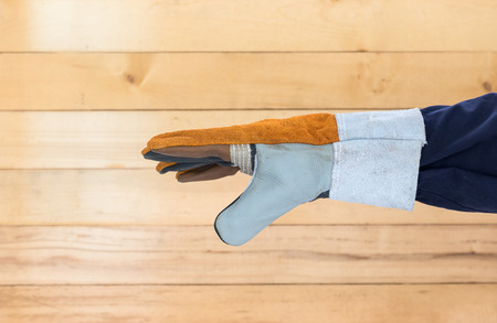 Working hand in Rough leather glove with wall wood background