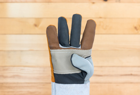 Working hand in Rough leather glove with wall wood background