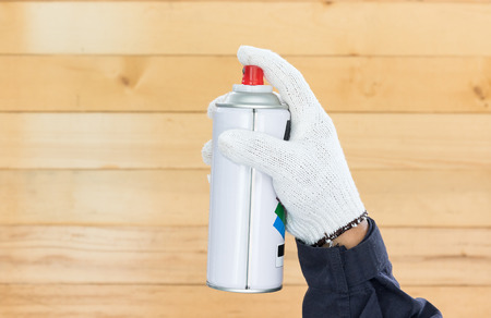 Working hand in glove holding spray paint can with wall wood backgroundの写真素材