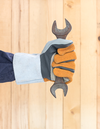 Working hand in glove holding a hammer with wall wood backgroundの写真素材