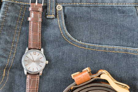 Top view of wrist watch on brown leather strap and leather belt in jeans pocketの写真素材