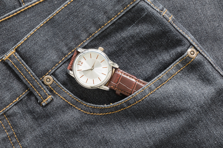 Wristwatch on brown leather strap in denim jeans pocket