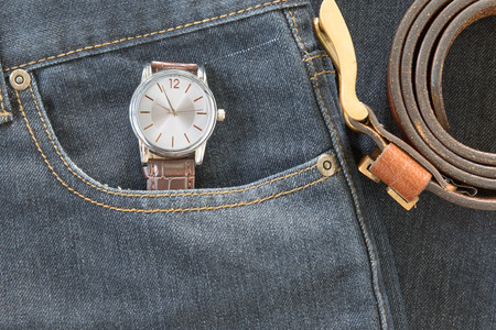 Top view of wrist watch on brown leather strap and leather belt in jeans pocketの写真素材