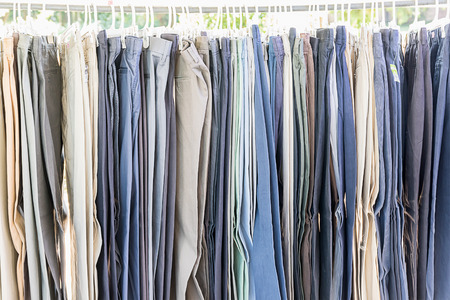 Close up row of various woolen trousers on hangers in tailoring atelierの写真素材