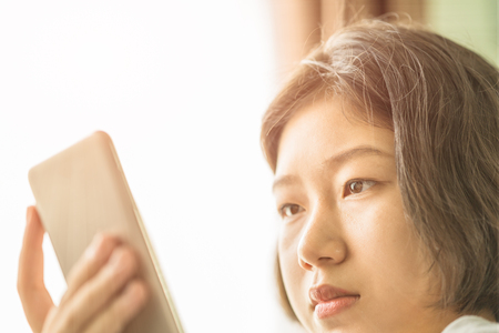 Close up young asian woman short hair listening music from mobile phone on the couchの写真素材