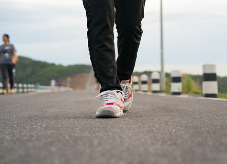 Close up young fitness woman and sneaker shoes walking on the roadの写真素材