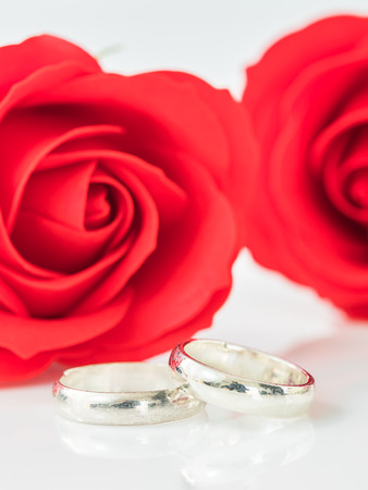 Close up red rose and wedding ring on white background, Wedding concept with roses and ringの写真素材