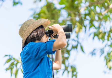 Close up Young asian woman short hair wear hat and hold binocular in grass field countryside...
