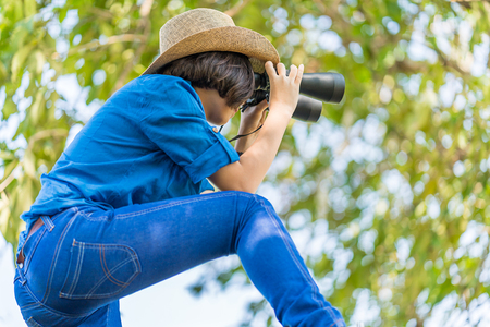 Close up Young asian woman short hair wear hat and hold binocular in grass field countryside Thailandの写真素材