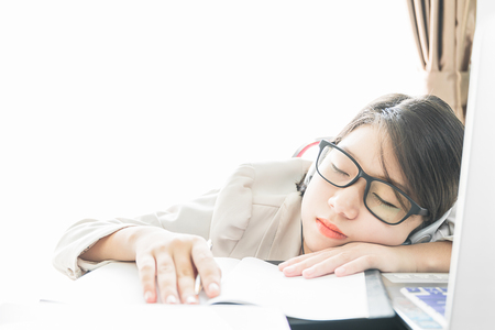 Teenage girl short hair sleep on desk after working on laptop while sit near window at home officeの写真素材