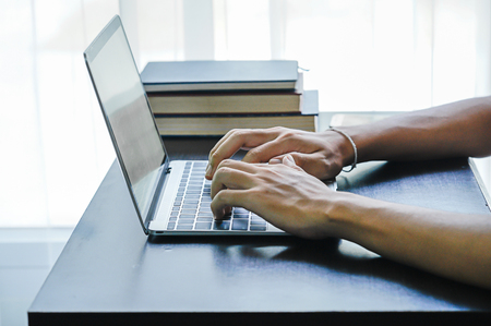 Male hands working with a Laptop computer on the table working at homeの写真素材