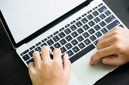Male hands working with a Laptop computer on the table working at homeの写真素材
