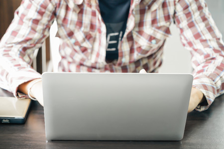 Male hands working with a Laptop computer on the table working at homeの写真素材