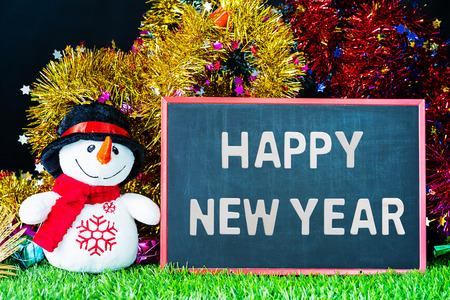Happy New year,Holiday decoration and snow man on green grass with chalkboardの写真素材