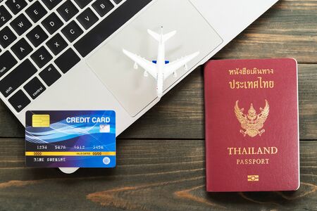 Passport with  credit card on laptop keyboard on a brown wooden background, Preparation for Traveling conceptの写真素材