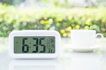 Close up Digital clock on table at office with coffee cupの写真素材