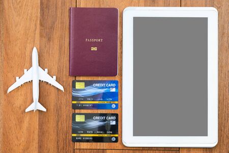 Top view Passport with credit card and digital tablet mock up on brown wooden desk background, Preparation for Traveling conceptの写真素材