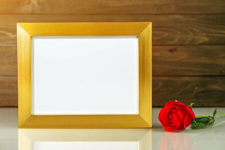 Picture mock up with golden frame and red roses flowers on table with copy spaceの写真素材