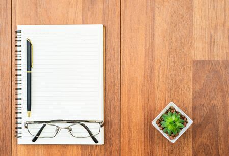 Top view eyeglasse and pen on notepad on wood deck with copyspaceの写真素材
