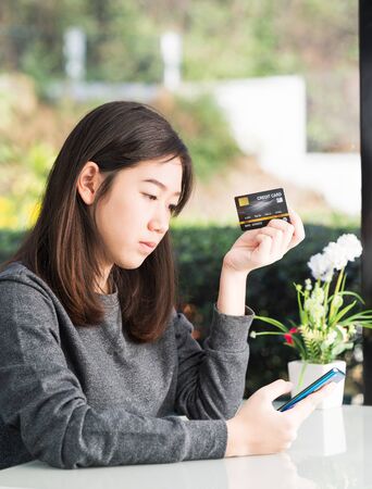 Young woman holding credit card and using smartphone for online shopping,Online shopping conceptの写真素材