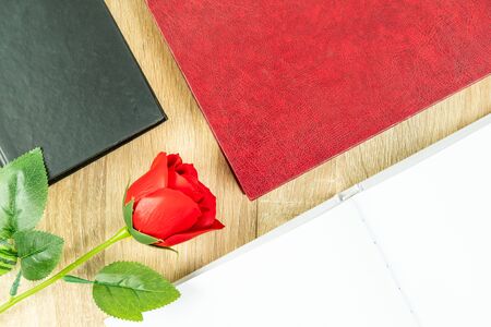 Top view shot of red roses and empty blank notebook diary and eye glasses with hardcover book on wood table,Valentine conceptの写真素材