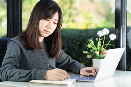 Teenage student using laptop doing homework at home. Learning online conceptの写真素材