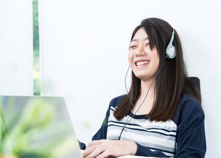 Young female student sitting in living room and learning online using laptop at desk .E-learningの写真素材