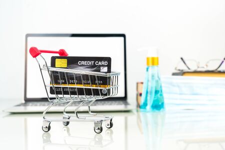 Credit card in shopping cart front of laptop screen with alcohol gel bottle , Work from home conceptの写真素材