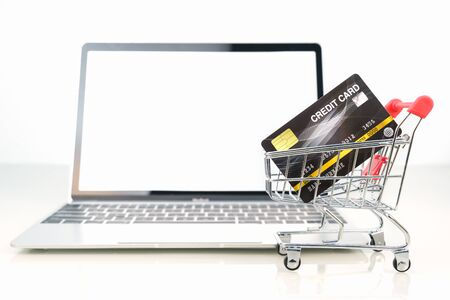 Credit card in shopping cart front of laptop blank screen for online shopping on white, Work from home conceptの写真素材