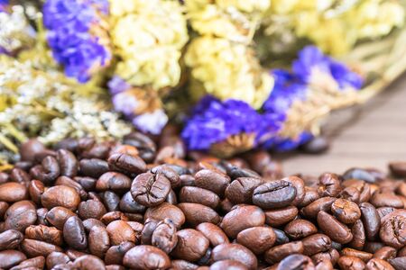 Close up roasted coffee beans heap with flower backgroundの写真素材