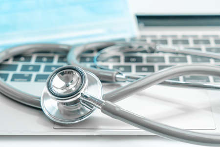 Medical stethoscope for doctor checkup on laptop with medical face masks as medical conceptの写真素材