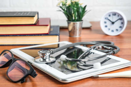 Medical stethoscope for doctor checkup with tablet computer on doctor table as medical conceptの写真素材