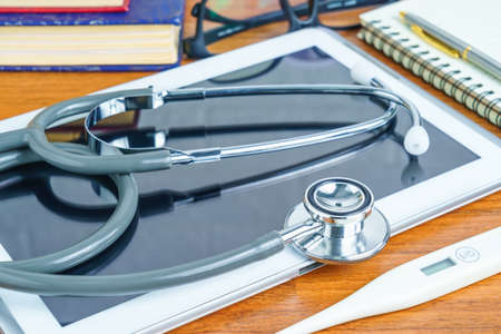 Medical stethoscope for doctor checkup with tablet computer on doctor table as medical conceptの写真素材