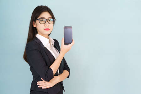 Young women in suit using her digital tablet standing against gray backgroundの写真素材