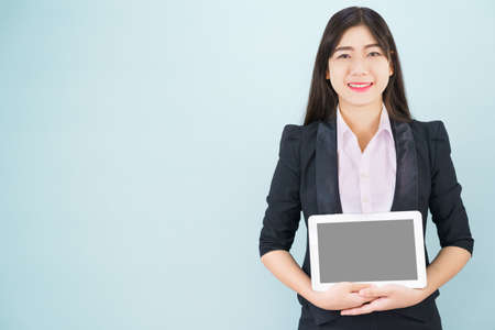 Young women in suit holding her smartphone standing against blue background