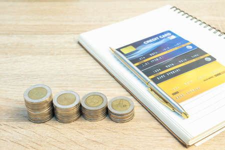 Top view coins with note pad and credit card on wood table using as financial concept
