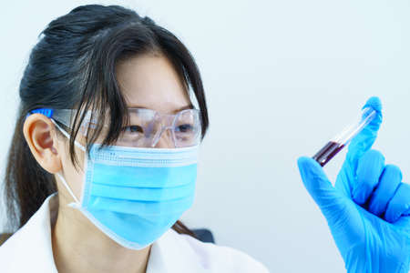 Technician scientist analyzing holding blood sample in test tube in laboratory for testing it on COVID, COVID-19, coronavirus virus analysisの写真素材