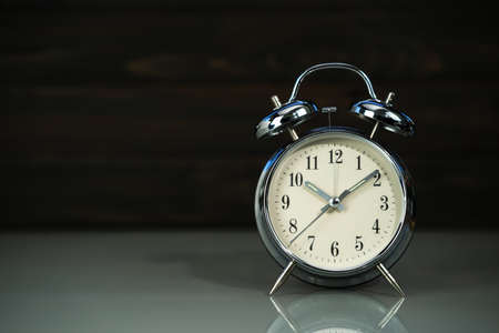 Retro alarm clock on table near wood backgroundの写真素材