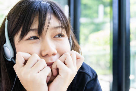 Teenage girl with headphones and listening to music from mobile phone at homeの写真素材