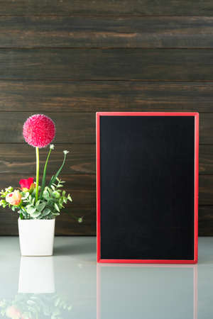 Flower vase and blank chalkboard on table near wood backgroundの写真素材
