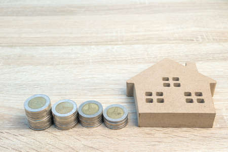 House model and coins on wood table using as property real estate and financial conceptの写真素材