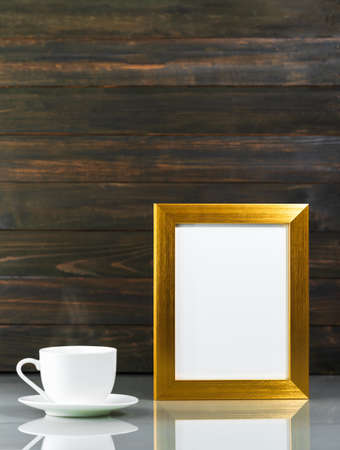 Picture mock up with golden frame and coffee cup over table with wood wall background