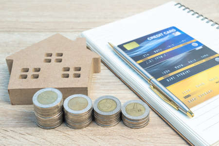 House model and coins with credit card on wood table using as property real estate and financial conceptの写真素材